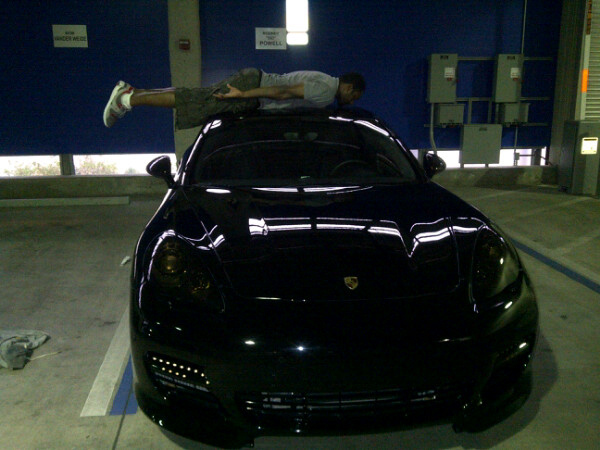 Gilbert Arenas visar upp sin svarta Porsche genom att planka på dess tak.