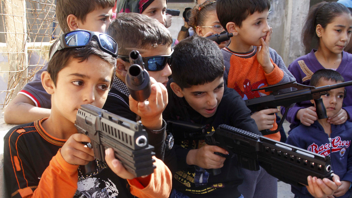 Syriska barn i ett flyktingläger leker med låtsasvapen och imiterar syriska rebeller.