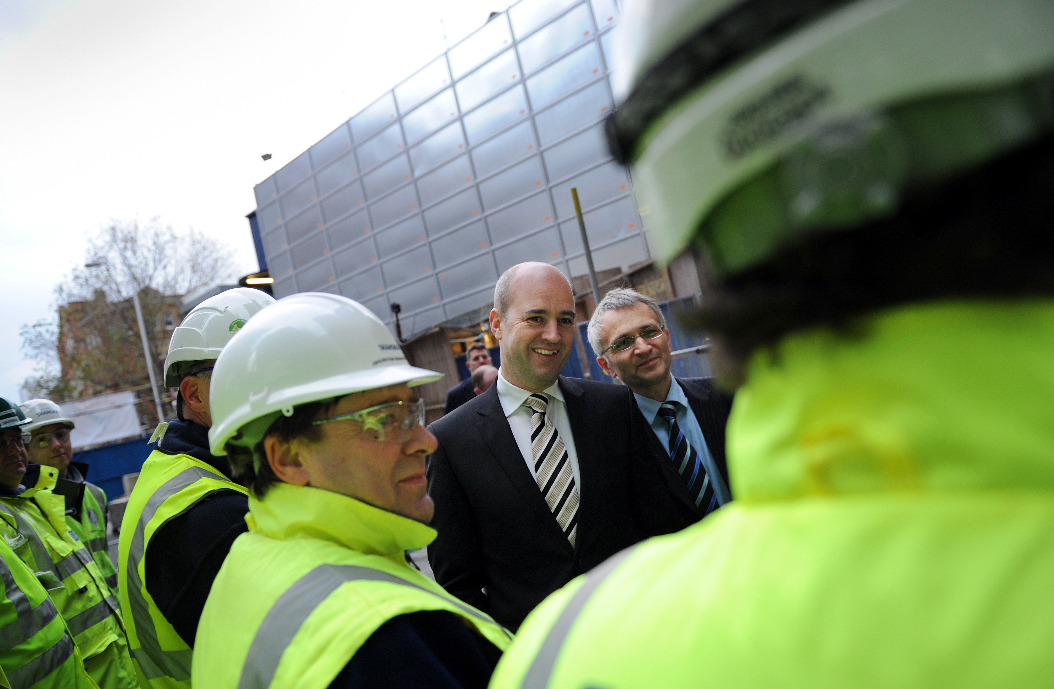 Reinfeldt är för tillfället på besök i Storbritannien - där hans motsvarighet, David Cameron, vill låna lite framgångsglans. Här snackar Reinfeldt med brittiska byggarbetare.