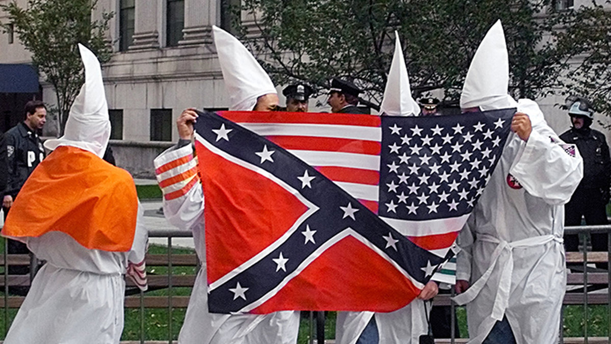 Medlemmar i Ku Klux Klan med en amerikansk flagga och en sydstatsflagga.