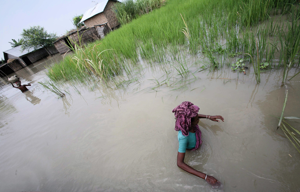 Lokalbefolkning vadar i vatten efter en tidigare översvämning i Bangladesh. Arkivbild.