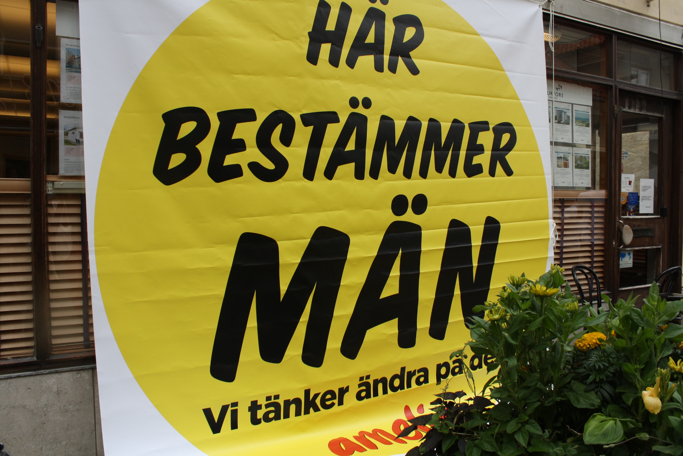Utanför Handelsbanken i Visby har Amelia satt upp affischen "Här bestämmer män. Vi tänker ändra på det!"