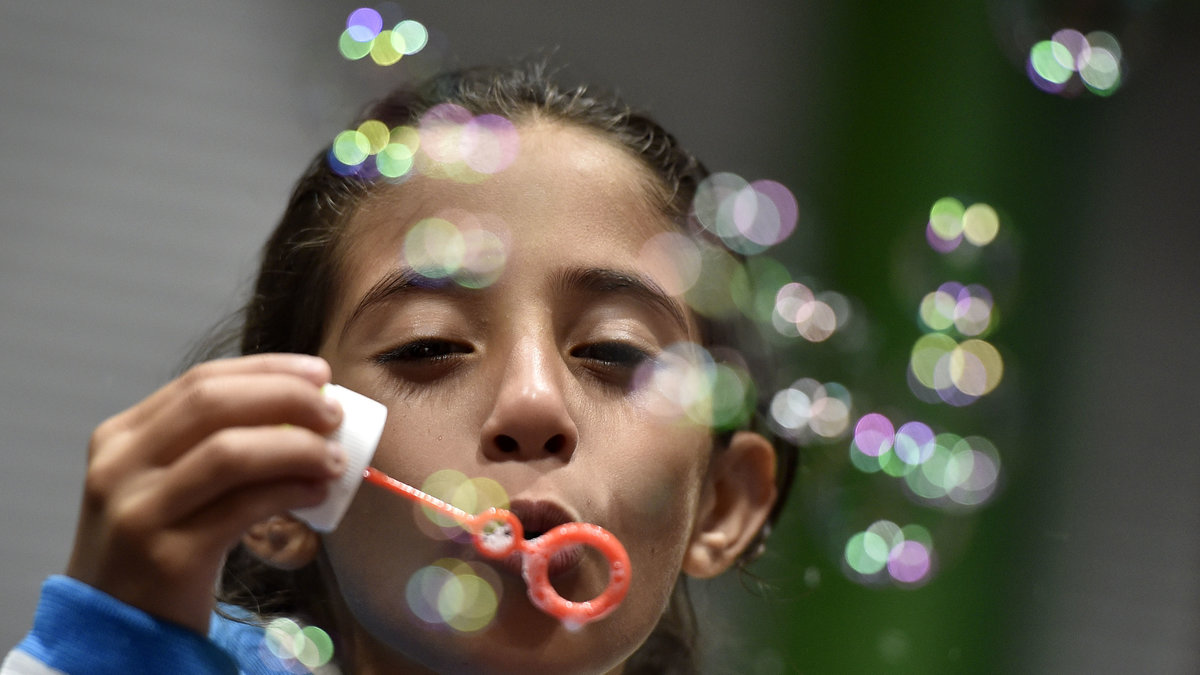 En flicka som är på flykt blåser såpbubblor i säkerhet i Tyskland. 