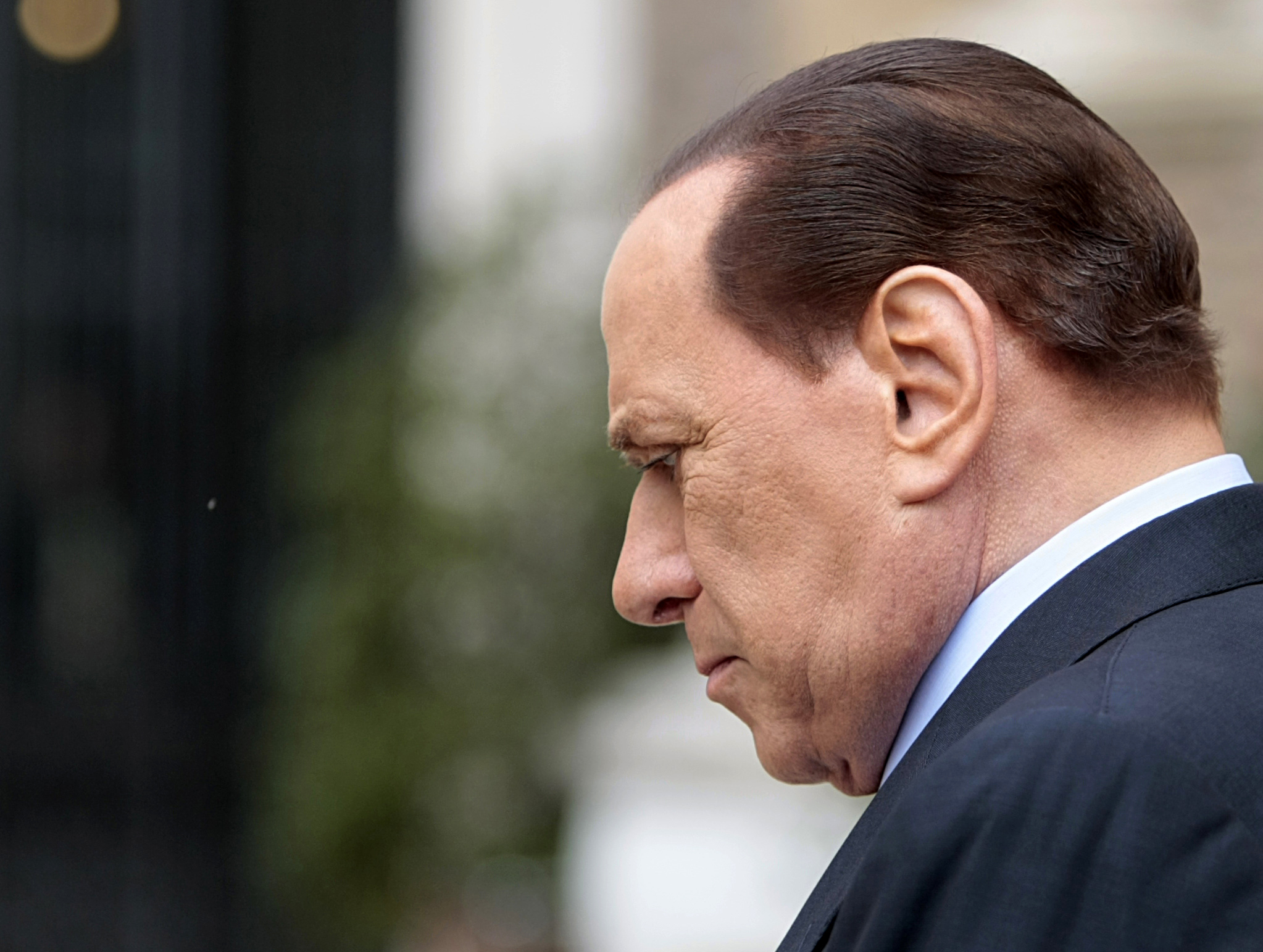 Silvio Berlusconi vandrar runt med en mindre munter min.