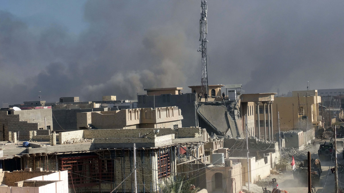 Rök stiger från staden efter att irakiska armén attackerat den statliga byggnad som kontrollerats av IS.
