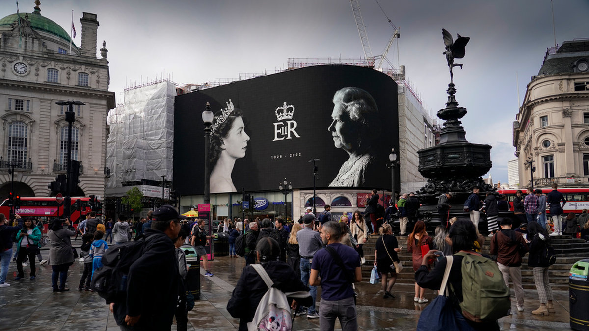 Drottning Elizabeths foto lyser upp en storbildsskärm på ett regnigt Piccadilly Circus i London.