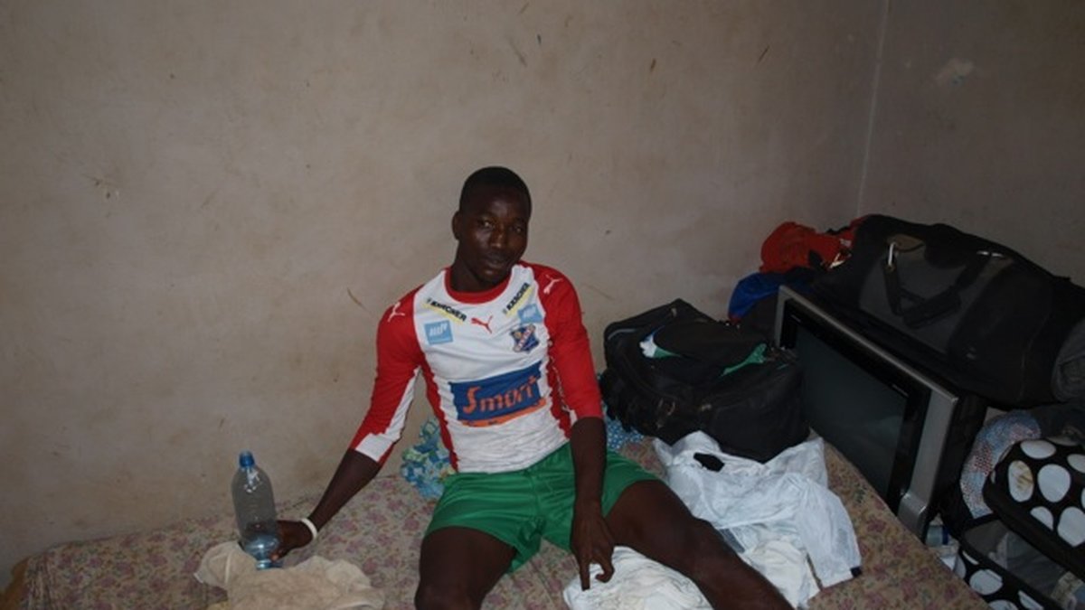Amadu Bella Barrie sitter på sin säng som han delade med tre andra fotbollsspelare i Freetown. 