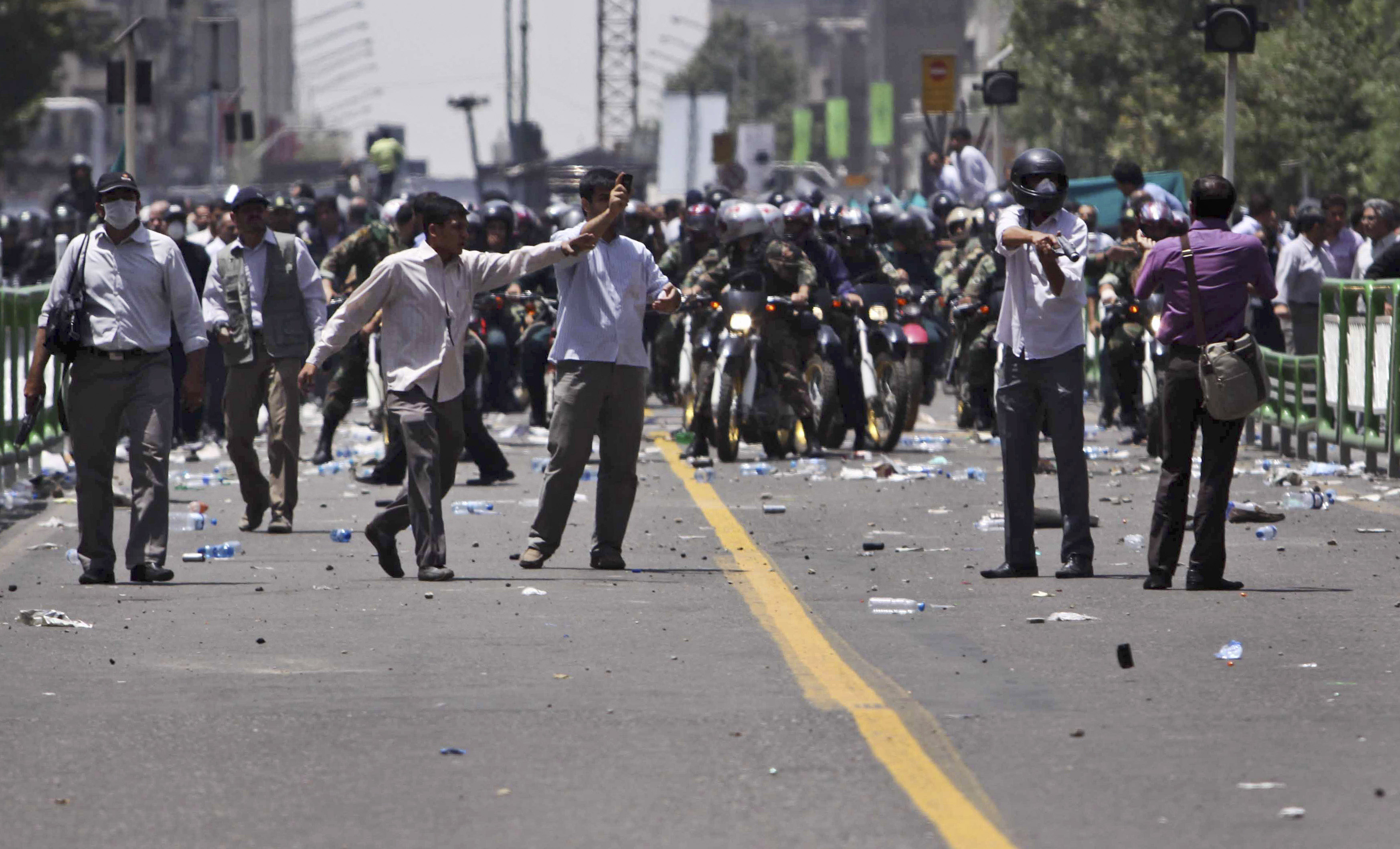 Till höger i bild ses en man ur en pro-regeringsmilis sikta med sin tårgaspistol mot en demonstrant.