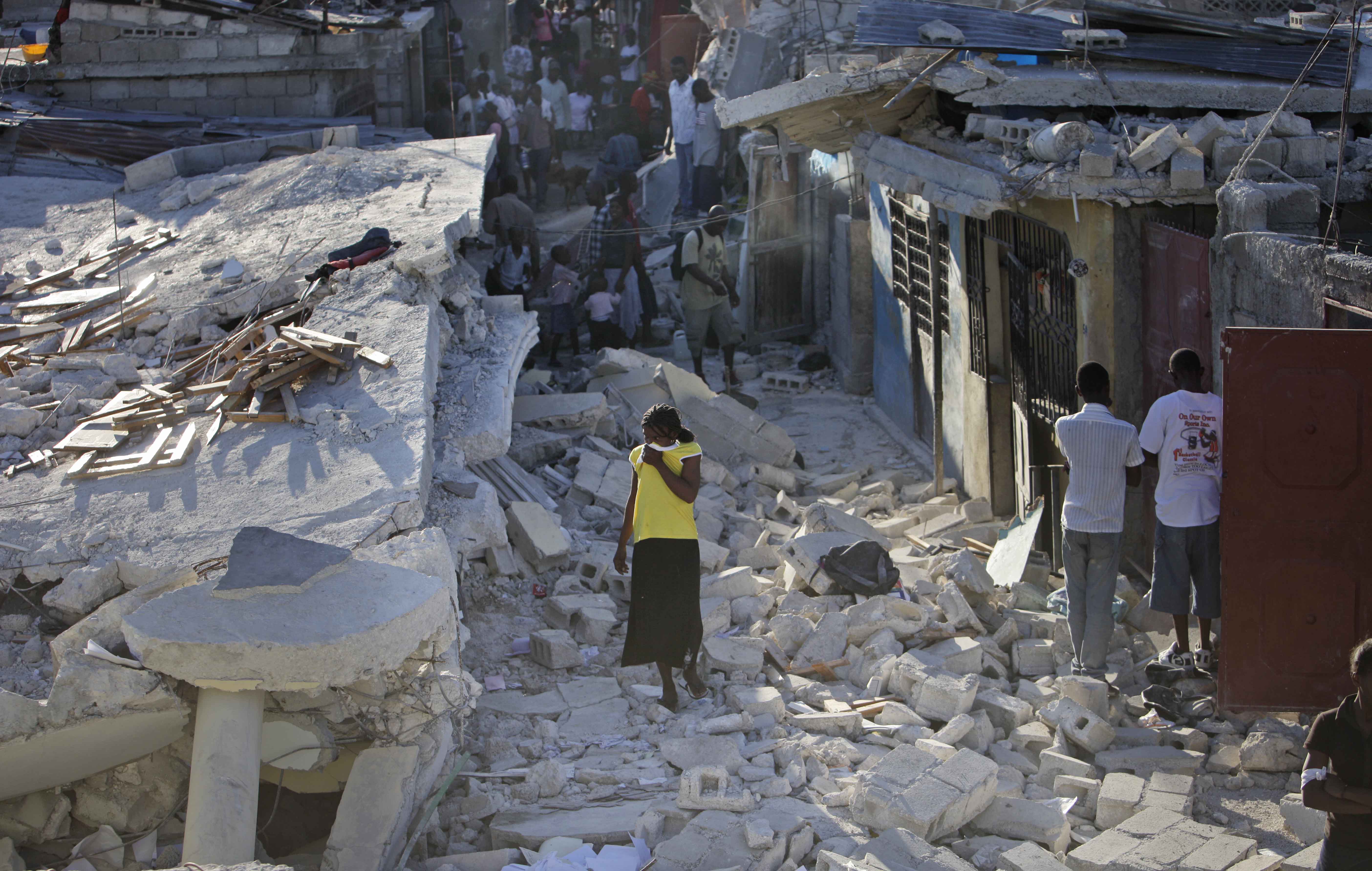 En kvinna på Haiti står mitt i ruinerna. 