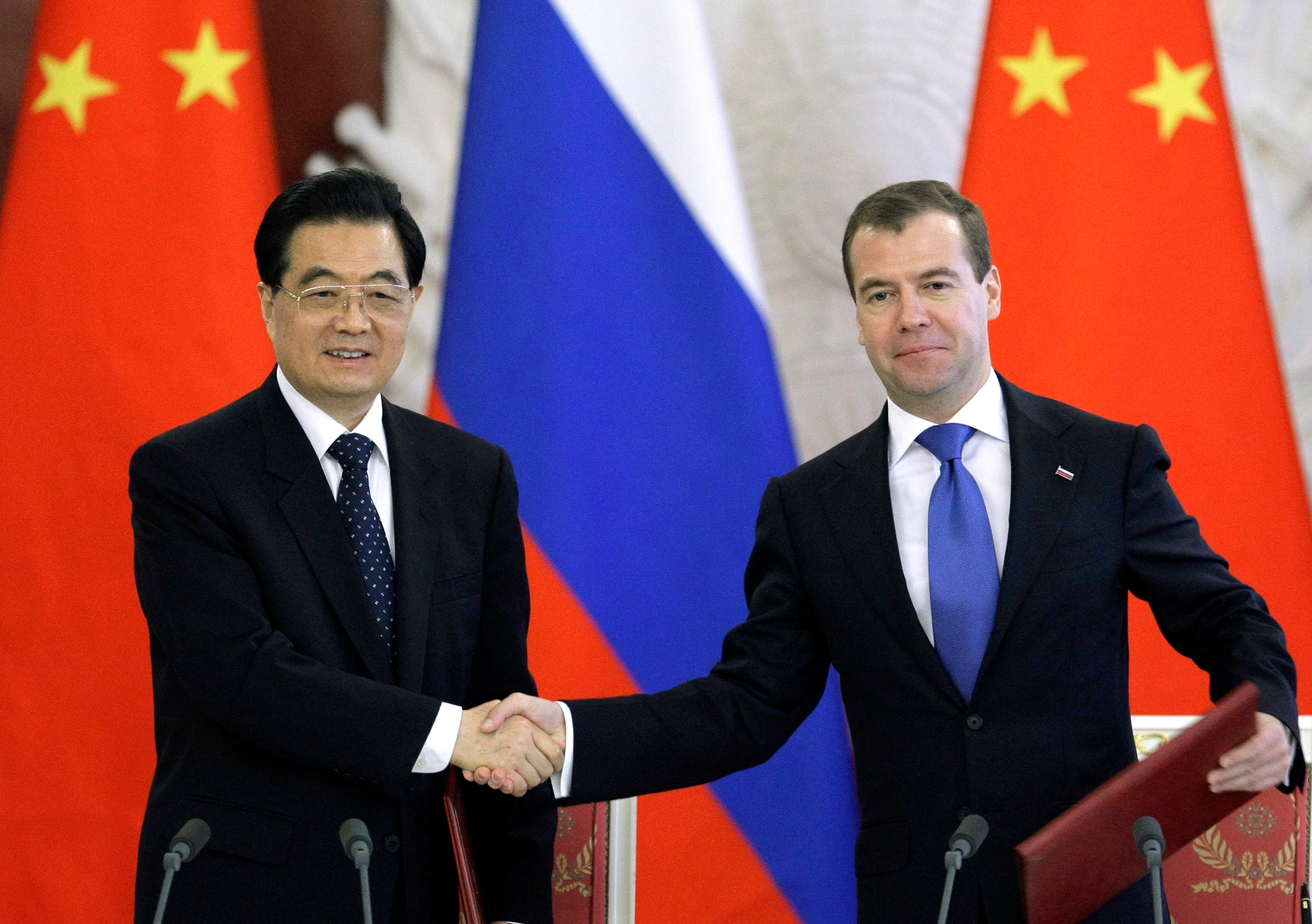Glada miner när Kinas president Hu Jintao och hans ryske motsvarighet Dmitri Medvedev skakar hand.