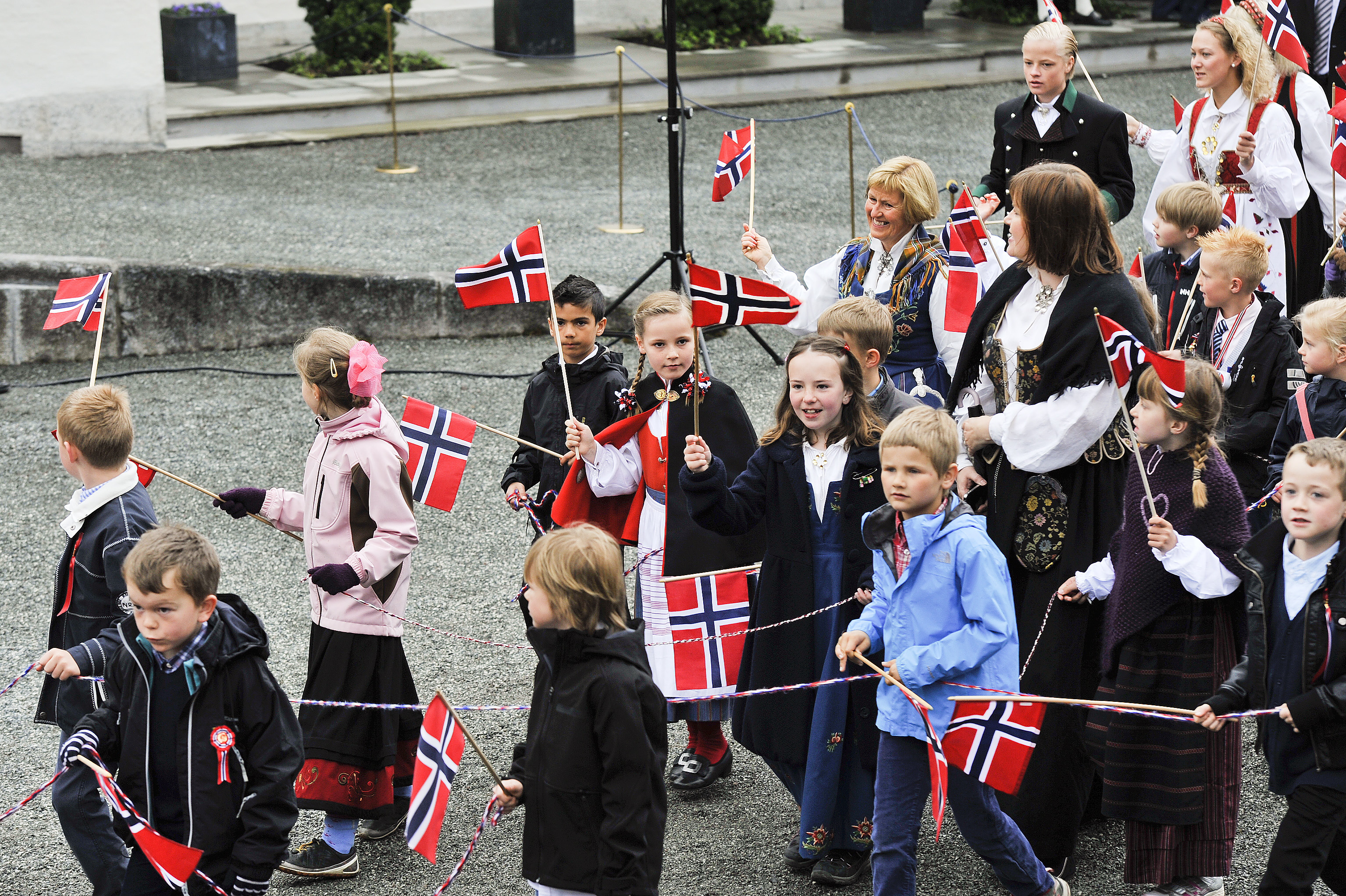 Tåg med flaggviftande barn besöker kungliga slottet. 