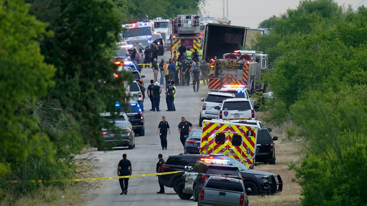 Polis, ambulans och räddningstjänst arbetar vid platsen där många migranter hittades döda i en lastbil i södra Texas i måndags.