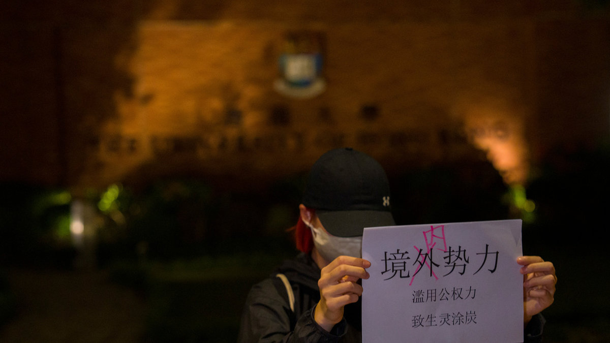En demonstrant vid ett universitet i Hongkong håller upp ett budskap som bland annat kritiserar maktfullkomlighet hos regeringen. Bilden togs på tisdagskvällen.