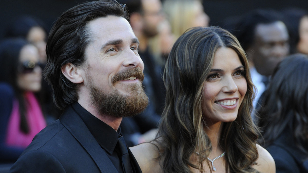 Christian Bale intar röda mattan med nästan lika långt hår som sin fru. 