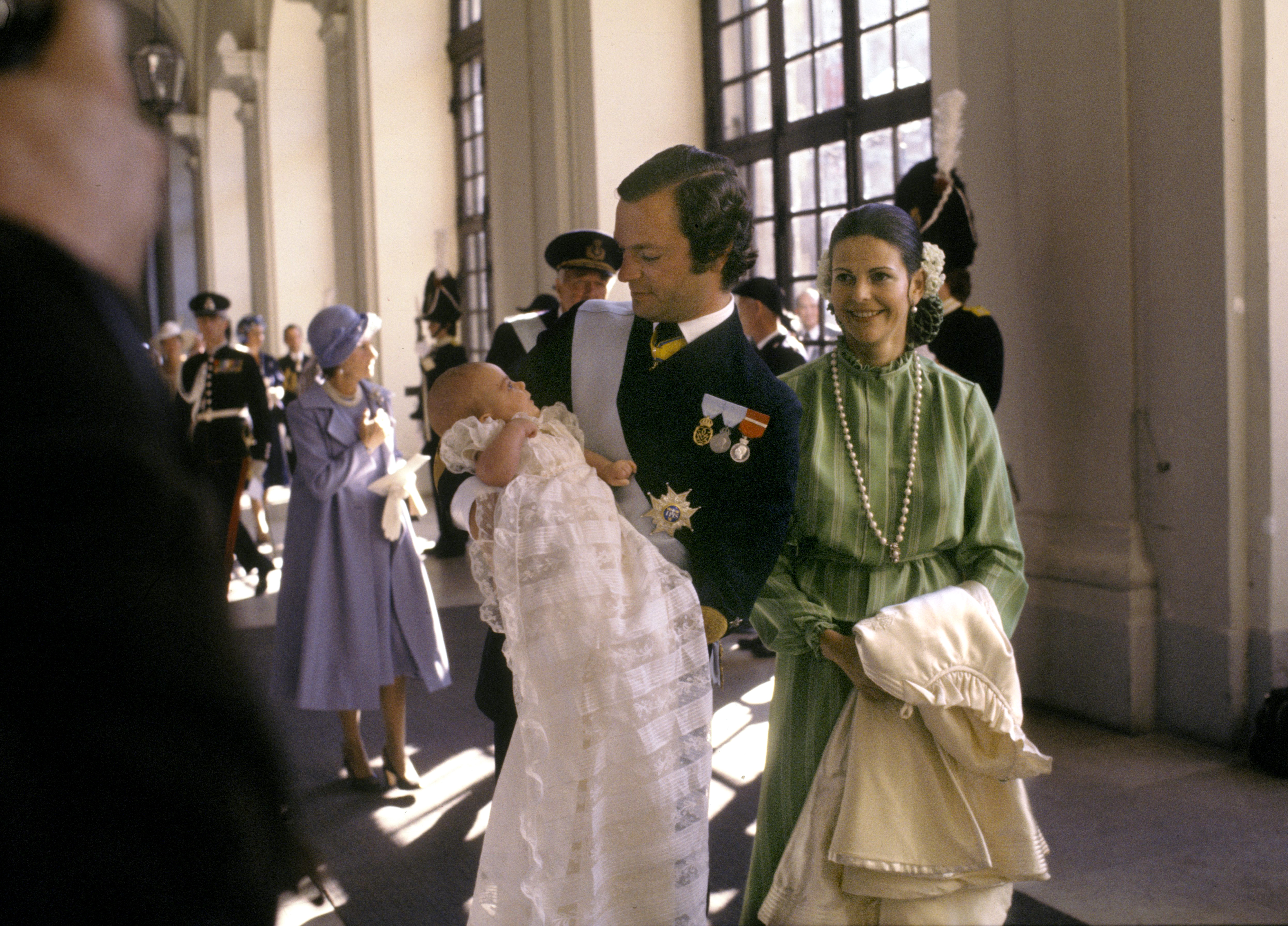 Kung Carl XVI Gustaf med prinsessan Victoria i famnen tillsammans med drottning Silvia på Stockholms slott 27:e september, 1977.
