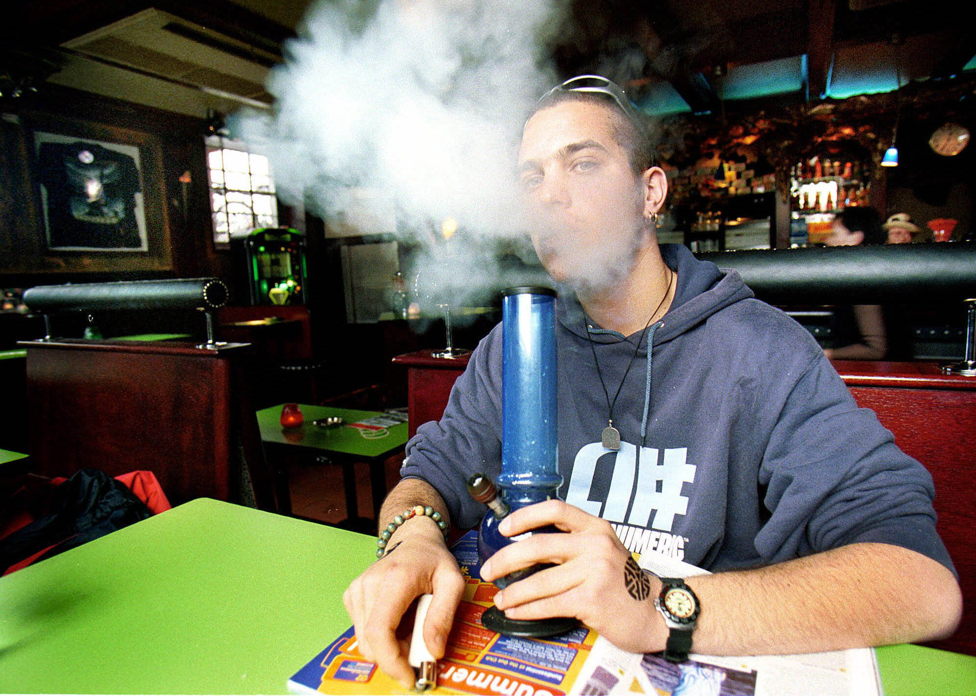 En australiensisk turist röker marijuana ur en vattenpipa på ett kafé i Amsterdam.