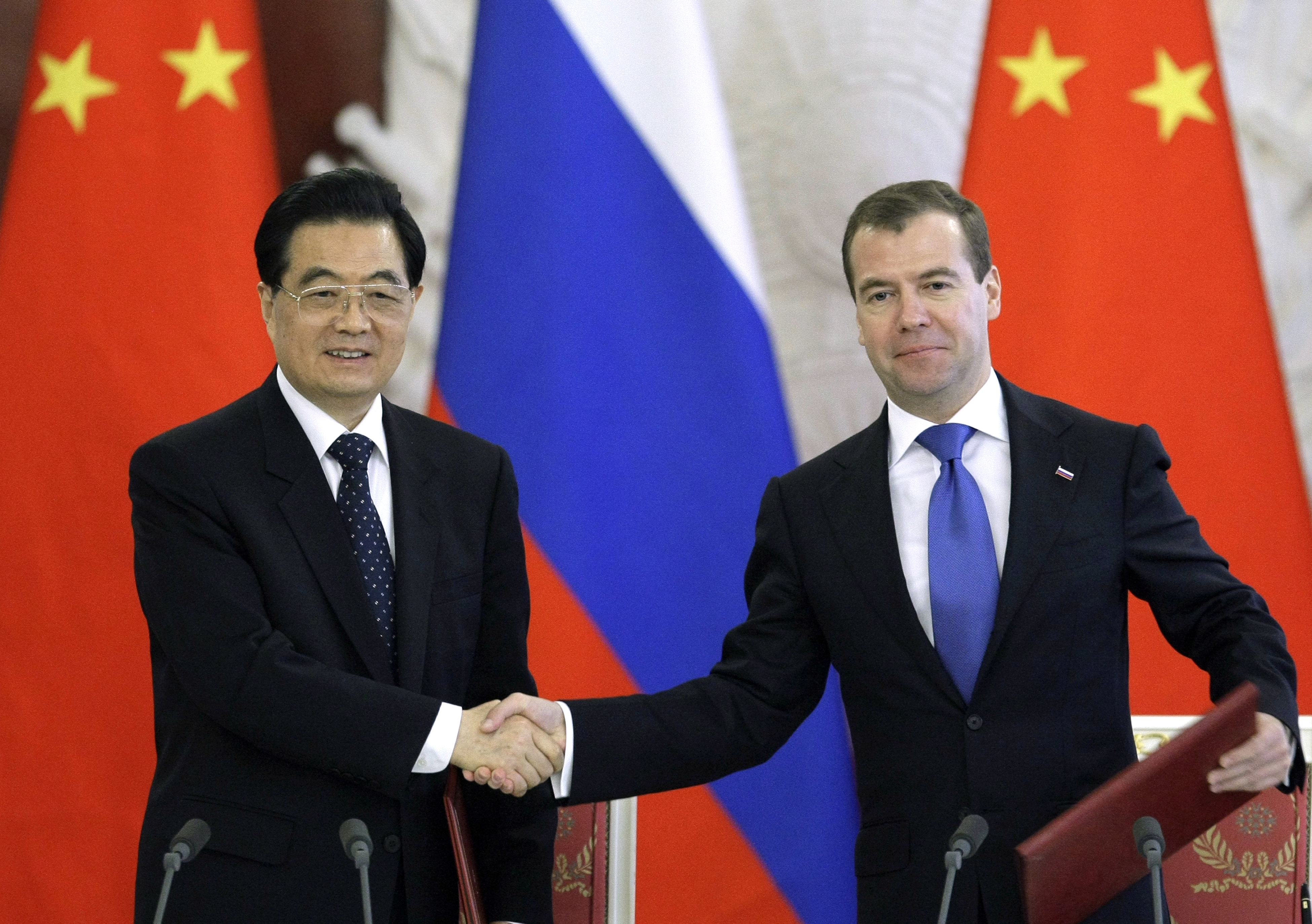 Glada miner när Kinas president Hu Jintao och hans ryske motsvarighet Dmitri Medvedev skakar hand.