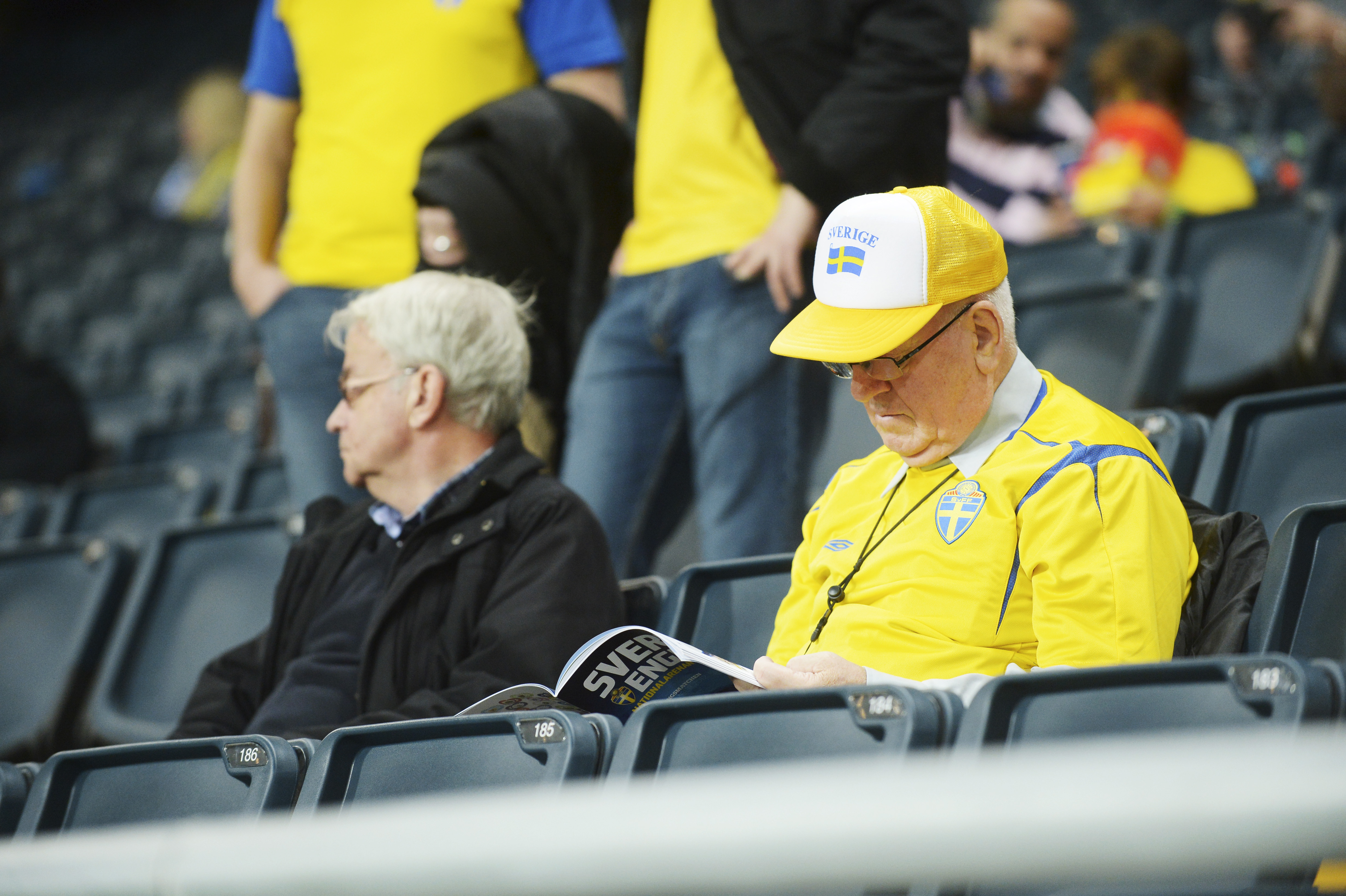 Publik som spanar in matchprogrammet. Publik som spanar in matchprogrammet.