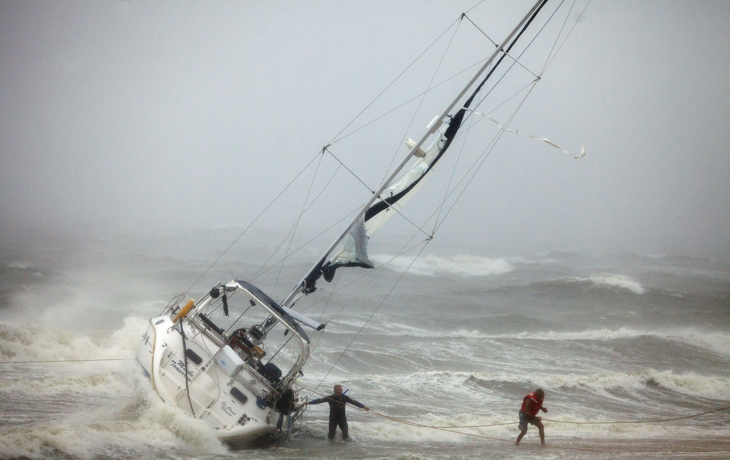 Personer räddas ur en segelbåt.