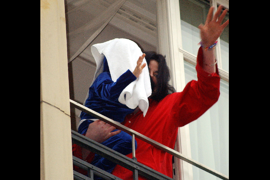 Samma år i Berlin. Michael Jackson vinkar till fansen från en balkong med ett av barnen i sin famn.  