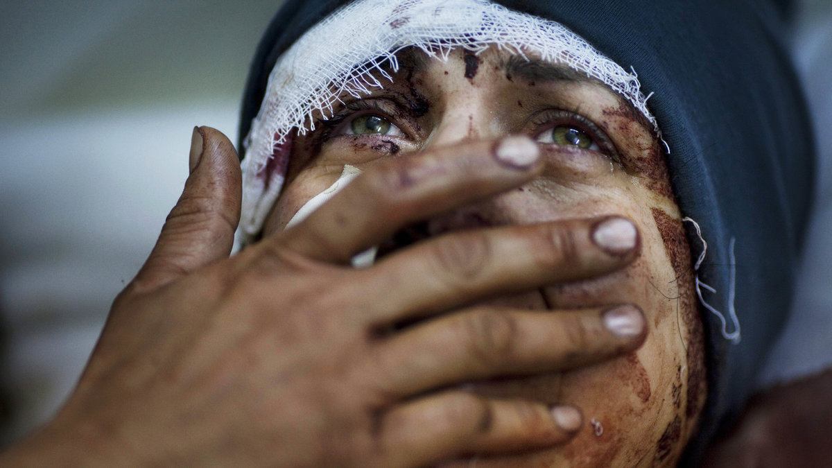 En kvinna gråter efter att ha förlorat sin man och två av sina barn när deras hus förstördes i ett bombattentat.