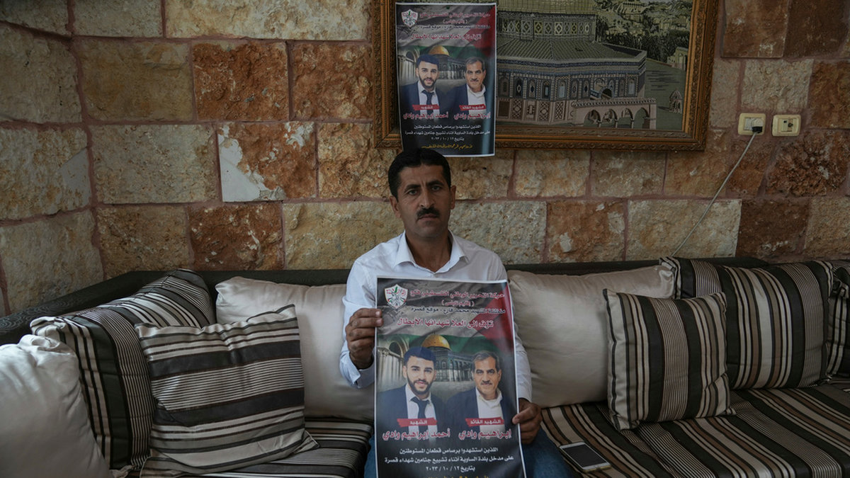 Palestiniern Abdelazim Wadi, 50, håller upp en plansch som tryckts till minne av hans bror och brorson som dödades av israeliska bosättare under en begravningsprocession i byn Qusra på Västbanken den 12 oktober. Arkivbild.