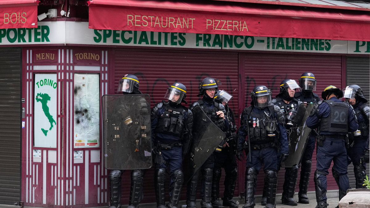 Fransk kravallpolis tar skydd bakom en restaurang utanför Paris i slutet av juni under de omfattande protesterna. Arkivbild.