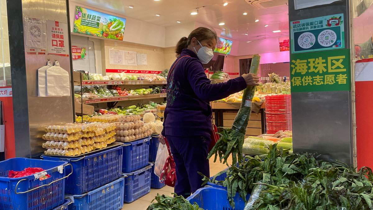 En kvinna i Kanton-provinsen handlar mat under torsdagen sedan en affär öppnat efter de lättade restriktionerna.