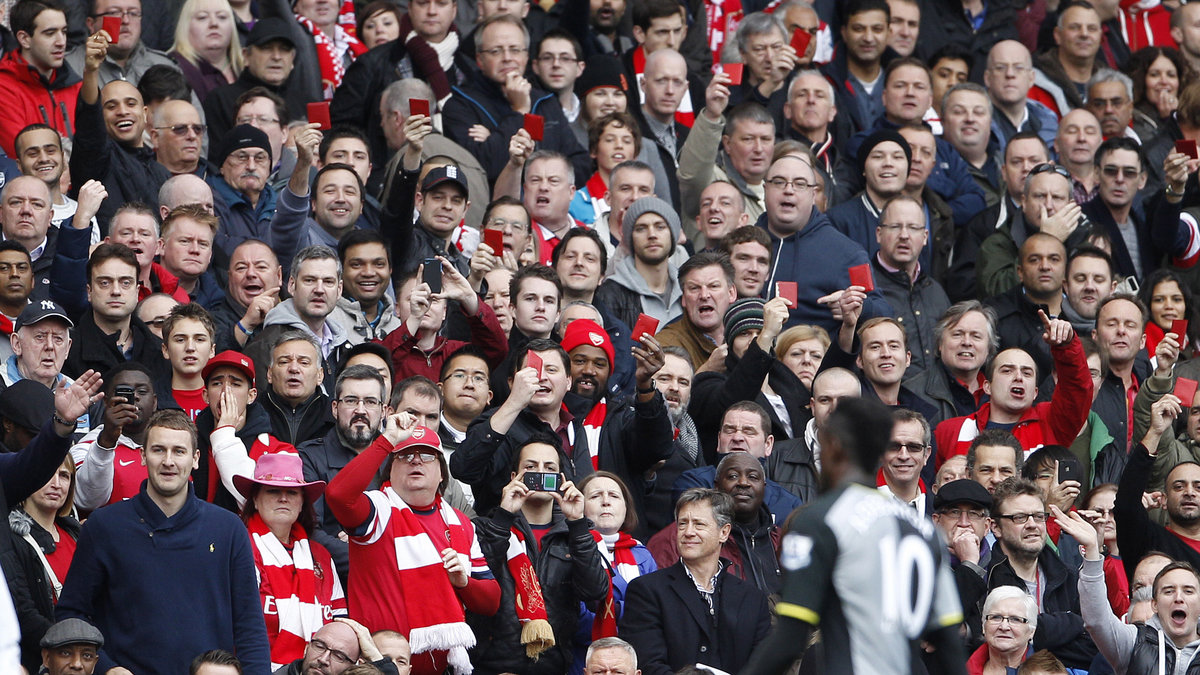 Arsenals supportrar viftar med sina röda säsongskort mot Adebayor.