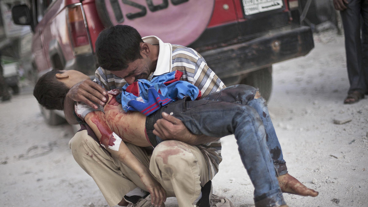 En man håller sin döda son, som dödats i en flygattack, oktober 2012. 