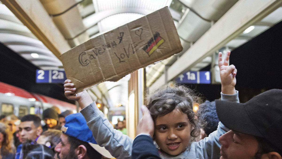 En flicka som kommit till Tyskland håller i en skylt som visar hur mycket hon älskar Tyskland.
