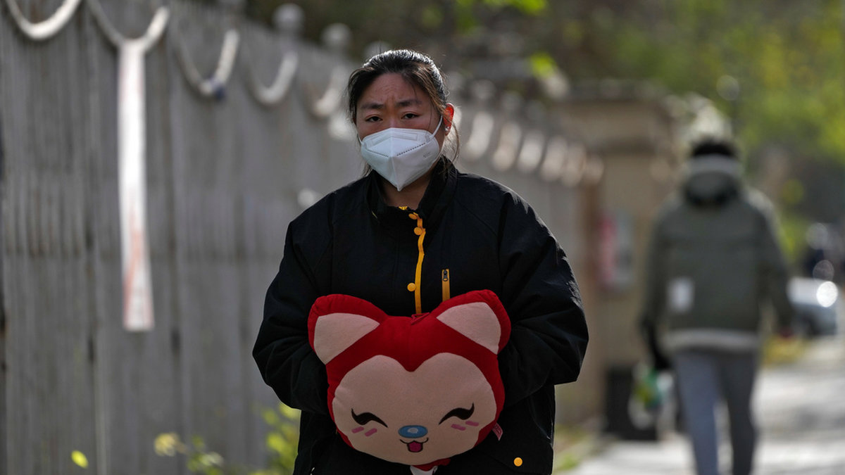 En kvinna värmer sina händer i iskylan i Peking under tisdagen. Universitet skickar hem sina studenter, och stor polisnärvaro i storstäder ska förhindra nya protester.