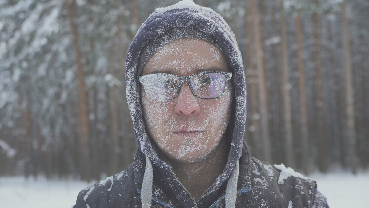 Man står i snöovädret och har imma för sina glasögon. 