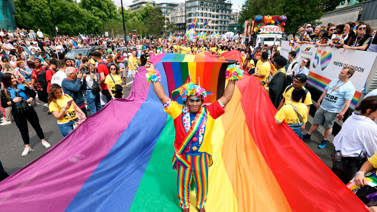 Londonbon Mohammed Nazir dansar på en jättelik regnbågsflagga under lördagens prideparad i den brittiska huvudstaden – som i år markerar att det är 50 år sedan priderörelsen drog i gång i staden.