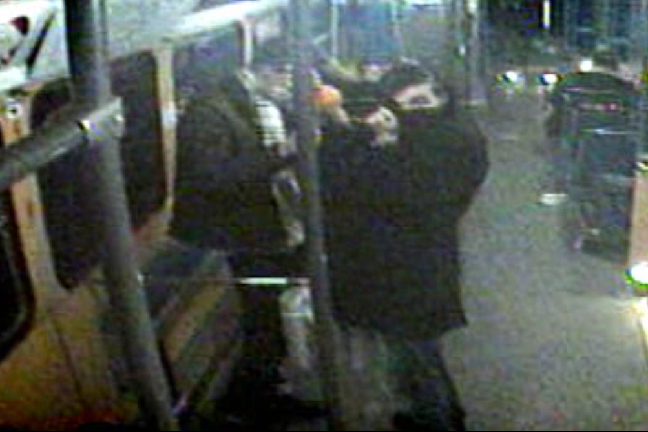 Två unga män kliver på spårvagnen och döljer sina ansikten för övervakningskameran.