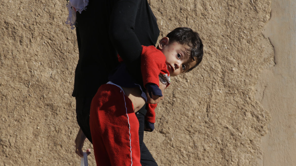 En kurdisk kvinna bär sitt barn i närheten av den syrisk-turkiska gränsen.
