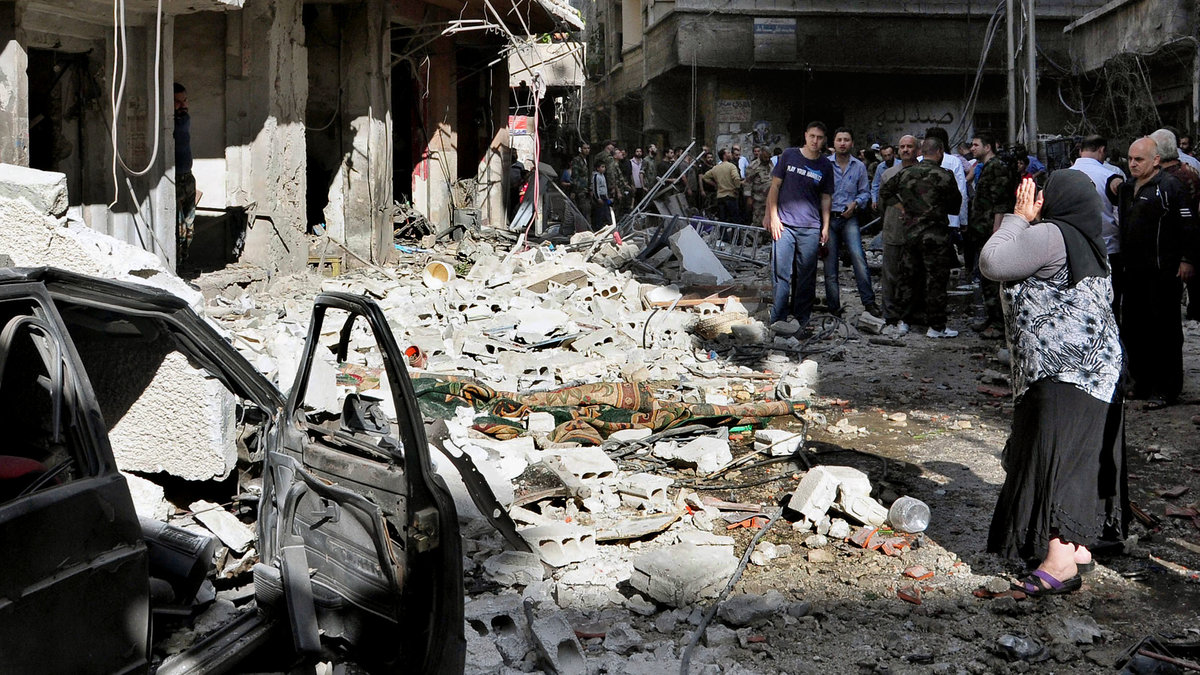 Invånare samlas för att inspektera skadorna efter att en bilbomb detonerat i Damaskus. Ett dussintal människor dog. September 2013.