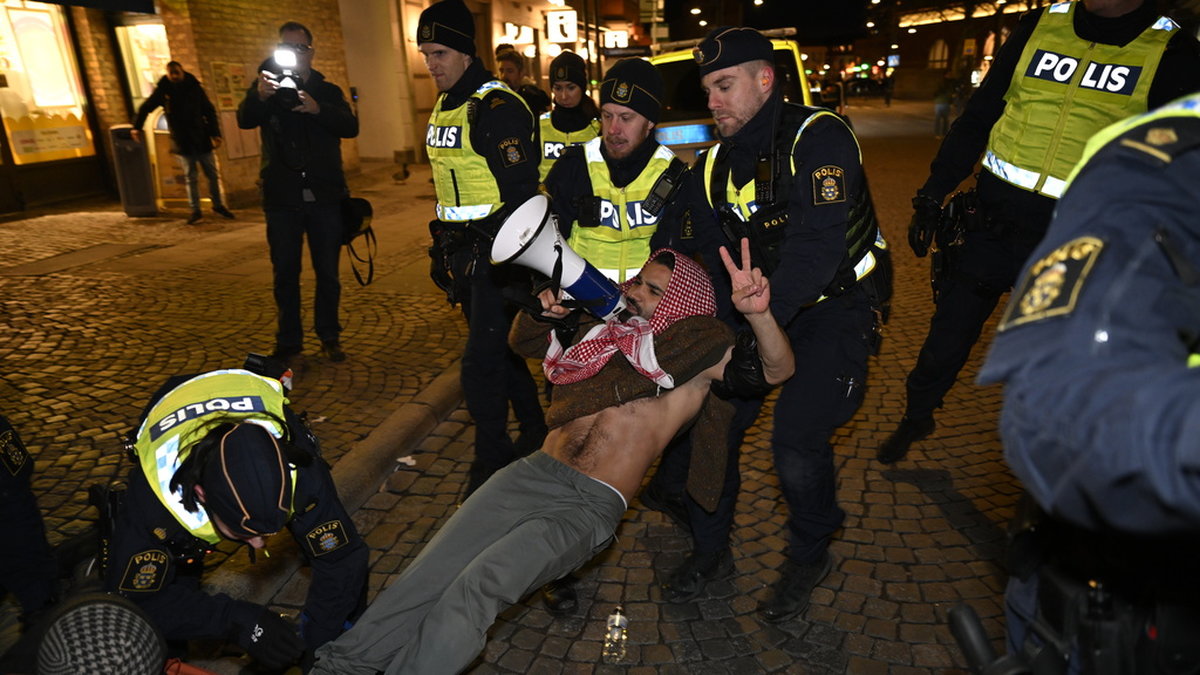 En person som protesterar på Stortorget tas om hand av polisen i samband med att statsminister Ulf Kristersson besöker Studentafton i Stadshallen i Lund.