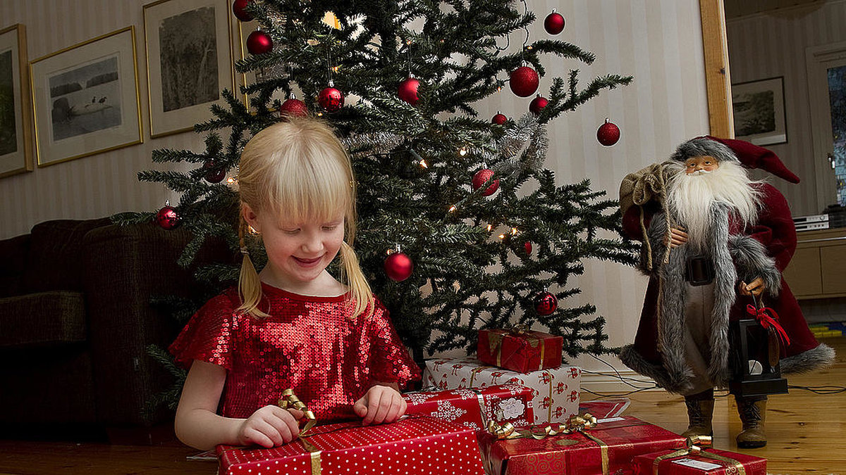 Julafton presenter julgran liten flicka med julklappar