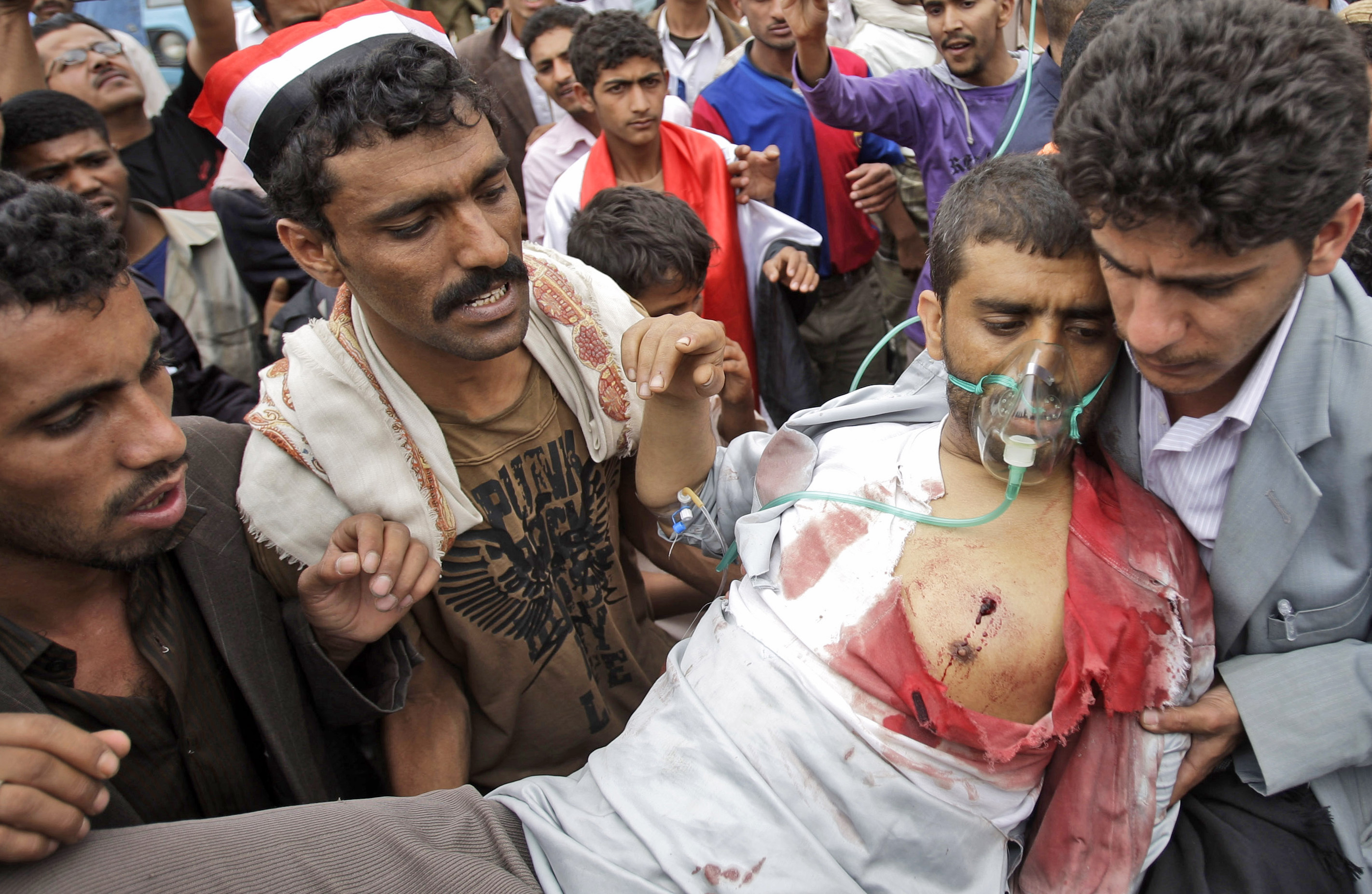 En skottskadad man bärs bort av sina meddemonstranter i Sanaa under onsdagen.