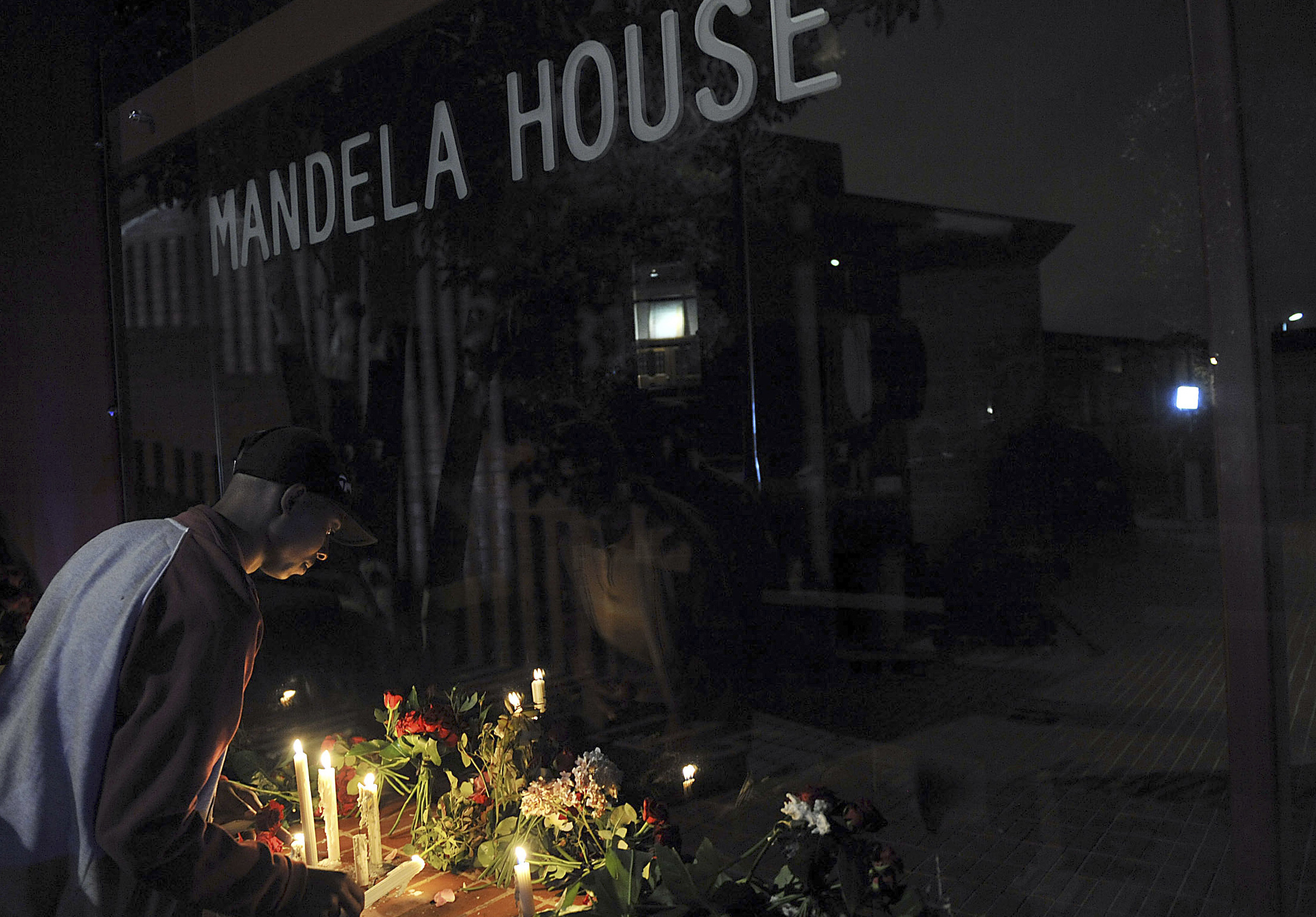 En man tänder ett ljus utanför Mandela House, hans tidigare hem, i Soweto. En man tänder ett ljus utanför Mandela House, hans tidigare hem, i Soweto.