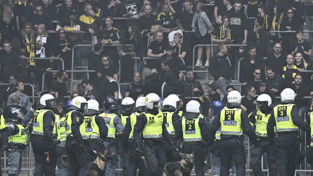Poliser med hundar på plan framför AIK:s supportrar under derbyt i maj. Arkivbild.