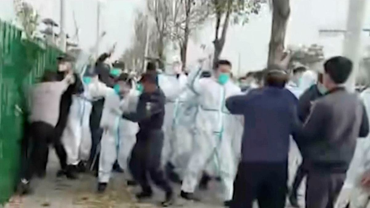 Protesterande möts av myndigheternas säkerhetsstyrkor i samband med oroligheterna kring Apple-fabriken i Zhengzhou.