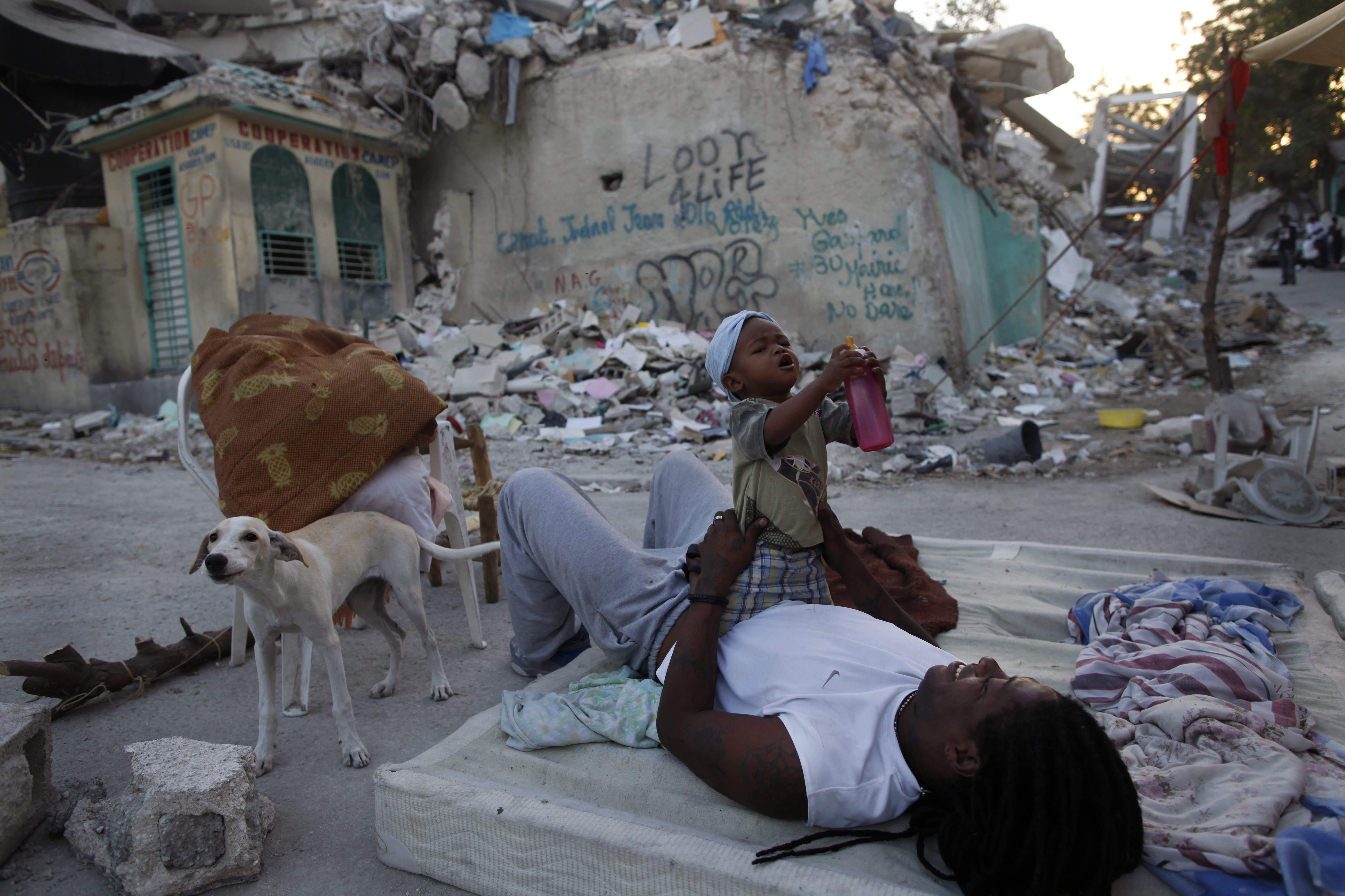 En kvinna leker med sitt barn i ruinernas Haiti.