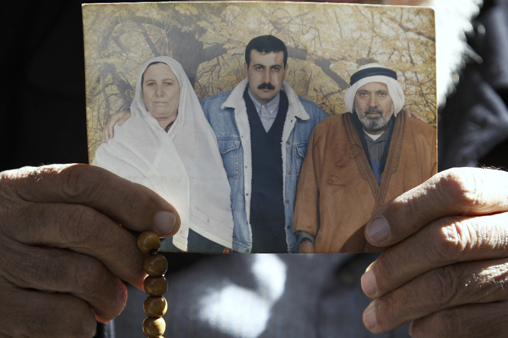 Mahmoud al-Mabhouhs pappa visar upp ett foto på sin döde son.