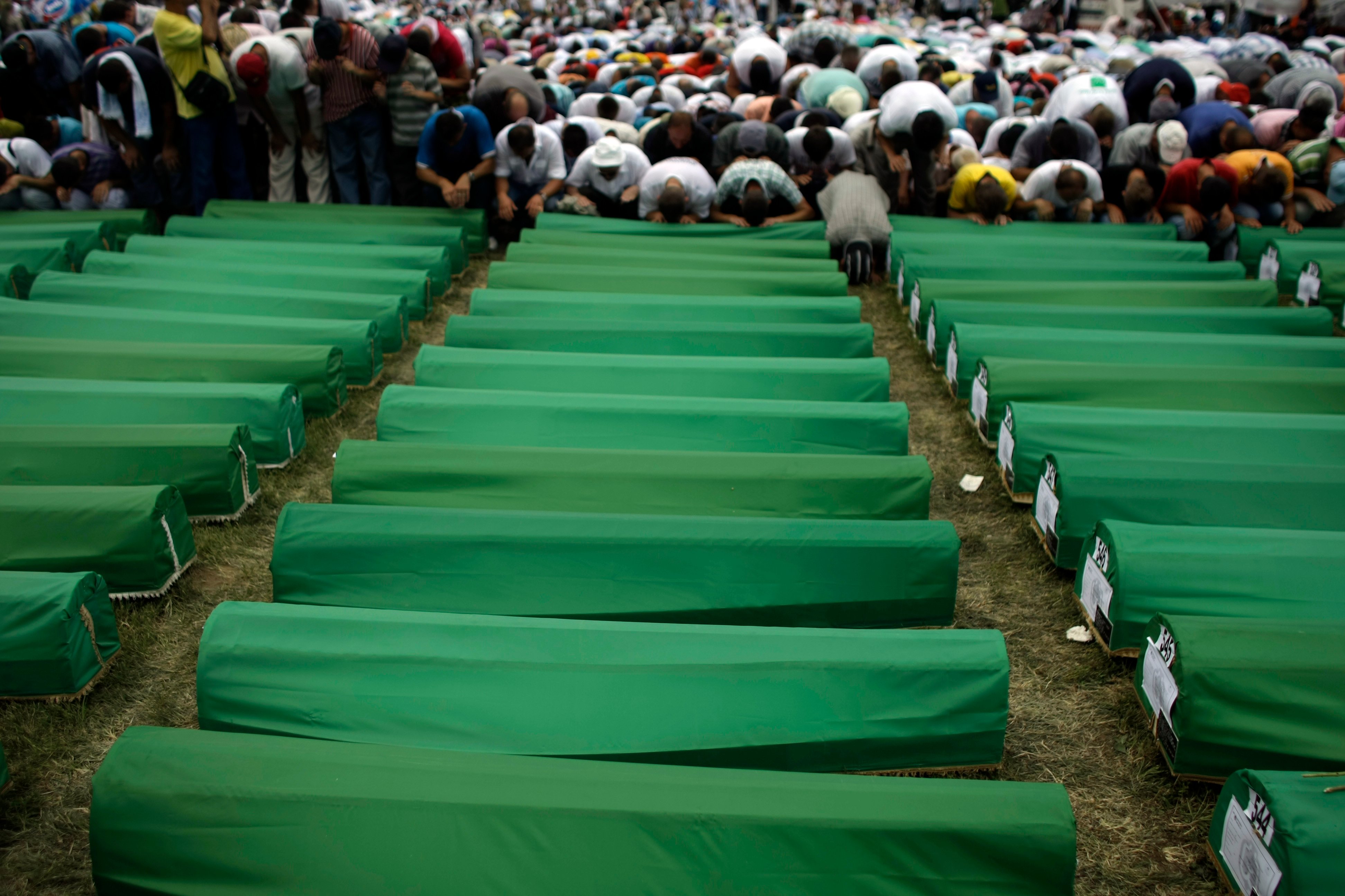 Muslimska män ber inför 600 kistor precis innan massbegravningen.
