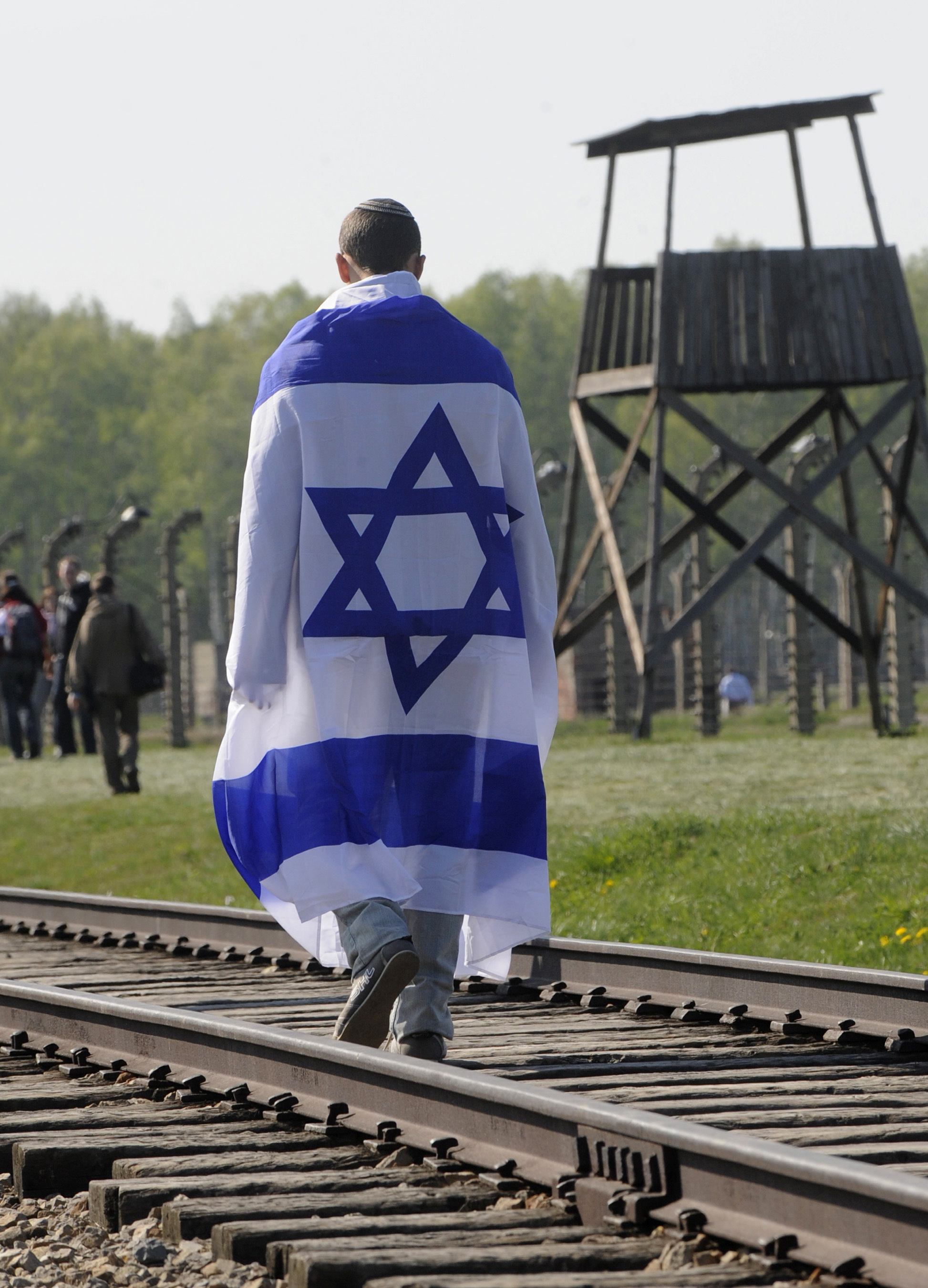 En man går tillsammans med den israeliska flaggan på spåret som ledde judarna in i Auschwitz.