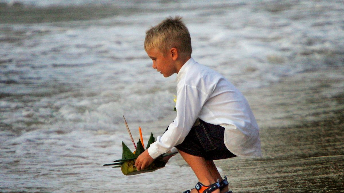 2005, ett år senare. En ung, svensk pojke sjösätter ett minnesljus för tsunamins offer, strax utanför Phuket. 