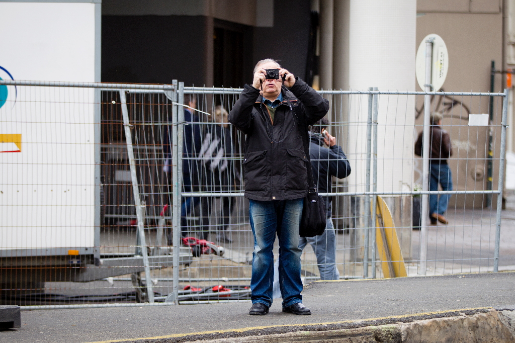 En man tar en bild av pressuppbådet utanför tingsrätten i Oslo.