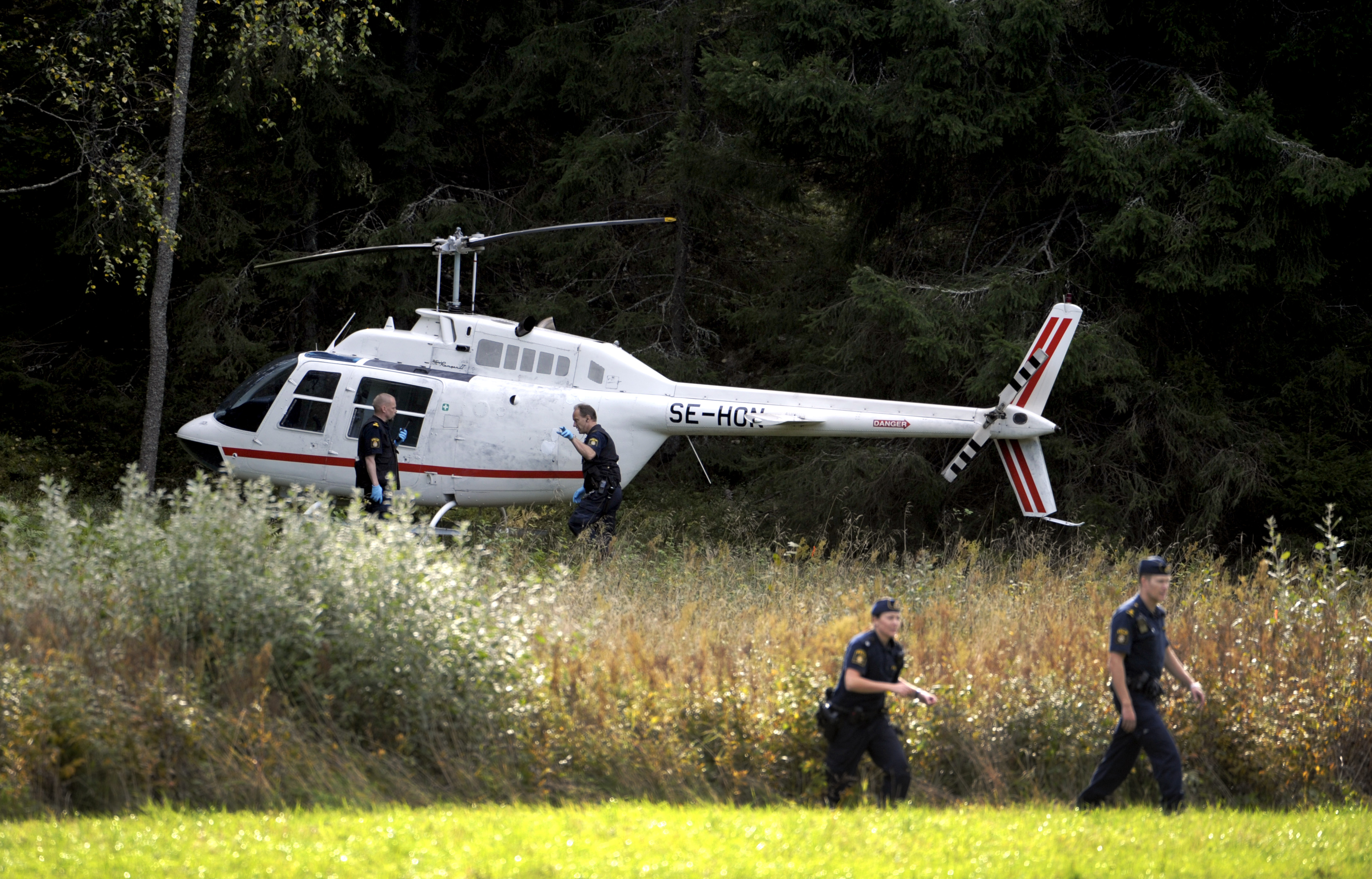 Polisen vid helikoptern som användes under rånet.